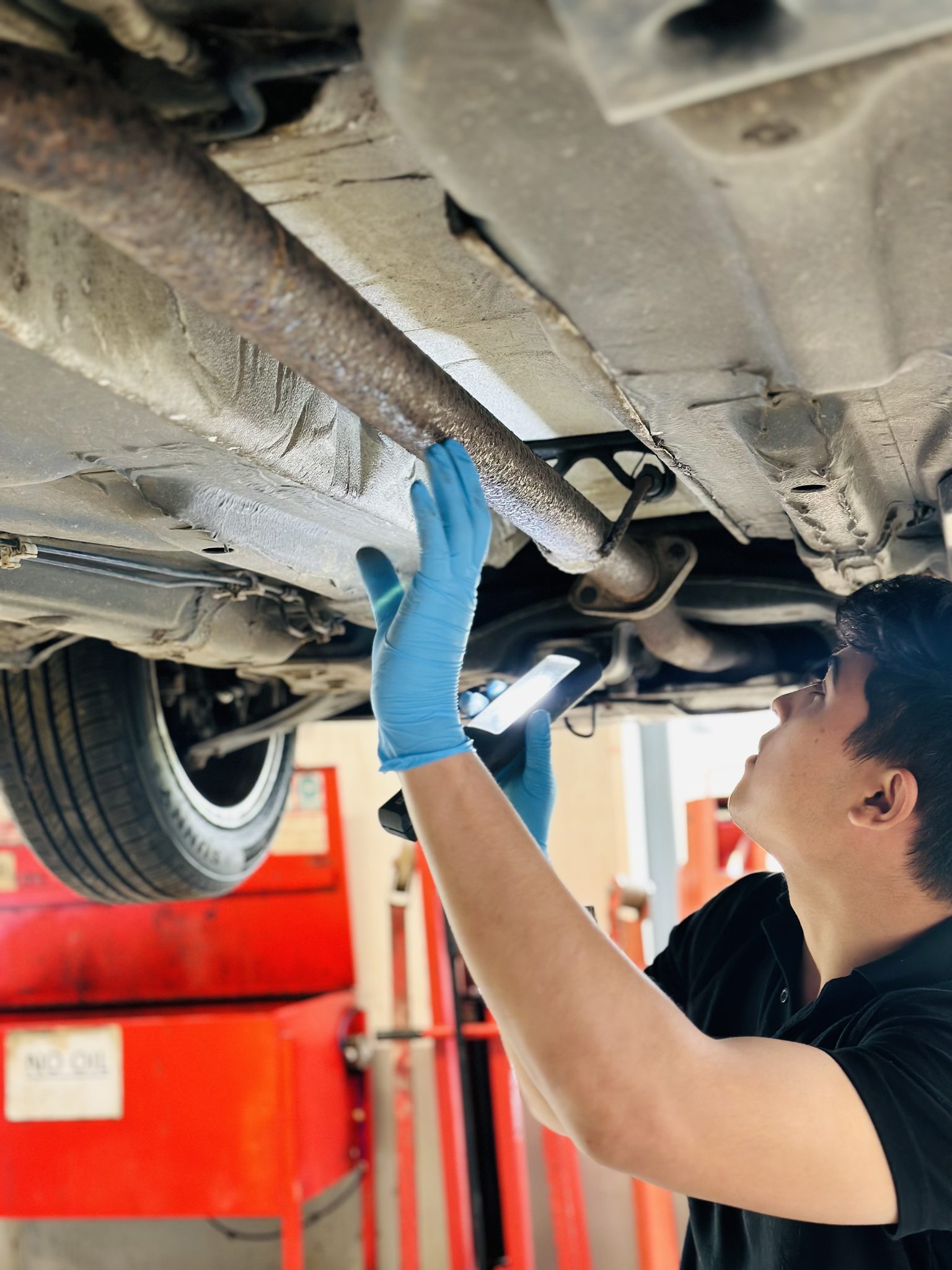 Mechanic inspecting vehicle underside at Salek garage, Ashford